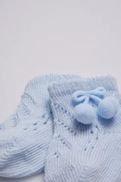 Calcetines perlé con borlas recién nacido celeste