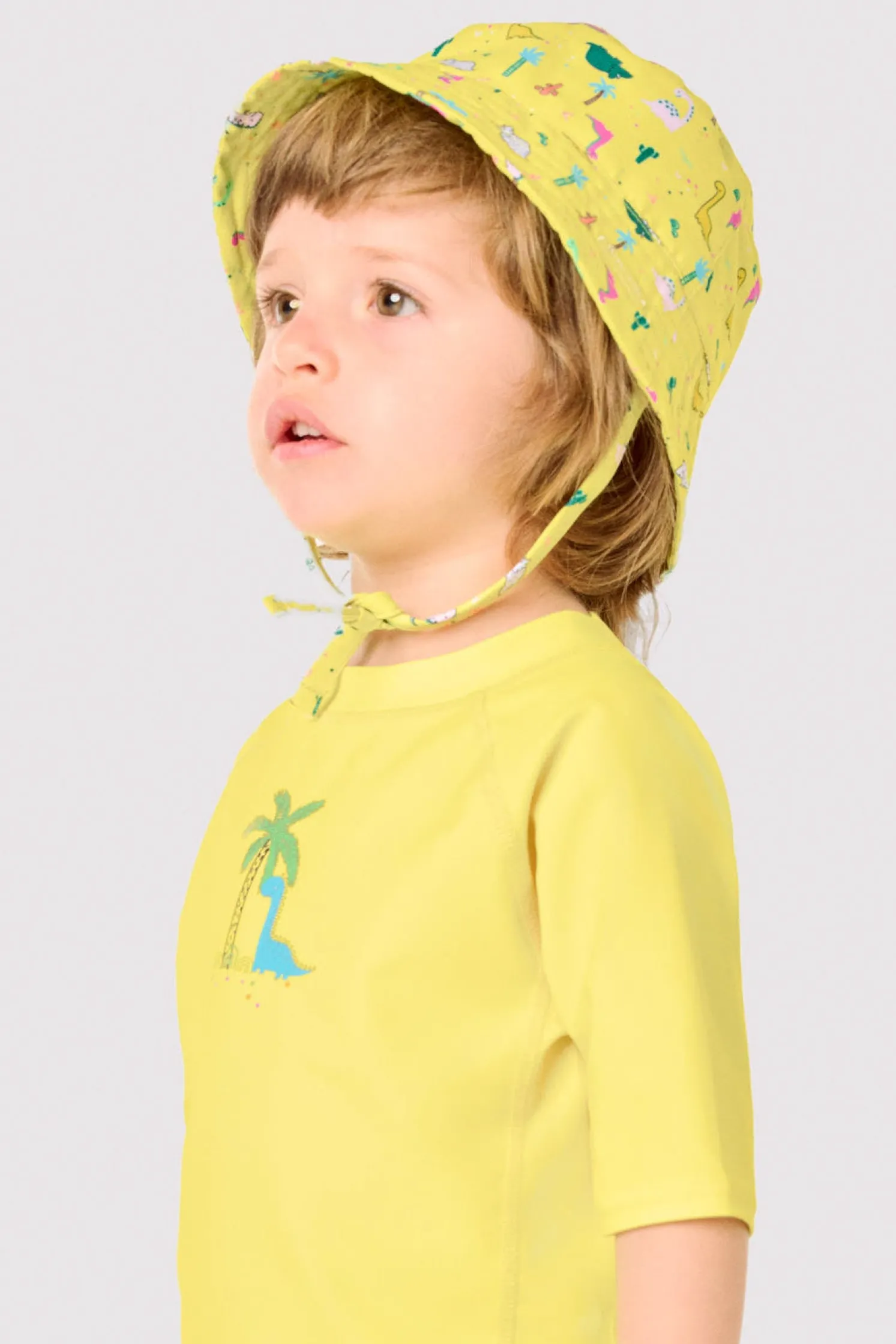 Gorro de playa bebé ala recta estampado dinosaurios amarillo
